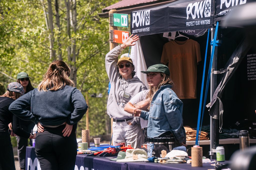two people at an event booth waving