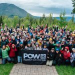 Large group with banner in front of mountains